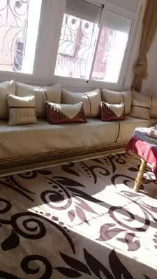 a living room with a couch with a large mirror at appartement meuble in Oulad Akkou