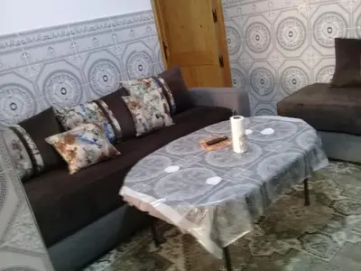 a living room with a couch and a table with a candle at appartement meuble in Oulad Akkou