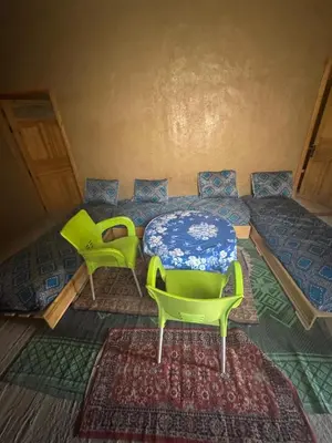 a room with two chairs and a table and a rug at Merzouga in Merzouga