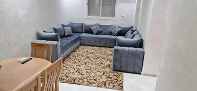 a living room with a blue couch and a table at Bahia Sakan in Oulad Akkou