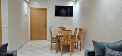 a dining room with a table and chairs and a television at Bahia Sakan in Oulad Akkou
