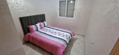 a bed with a pink blanket and a window at Bahia Sakan in Oulad Akkou