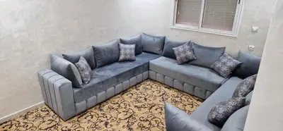 a living room with a blue couch with pillows at Bahia Sakan in Oulad Akkou