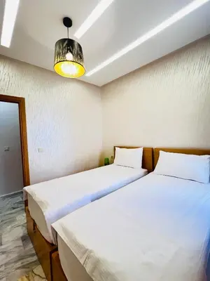 two beds in a small room with a light at Luxury Appartement fes city fleur in Fès