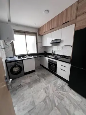 a kitchen with white cabinets and a marble floor at Luxury Appartement fes city fleur in Fès