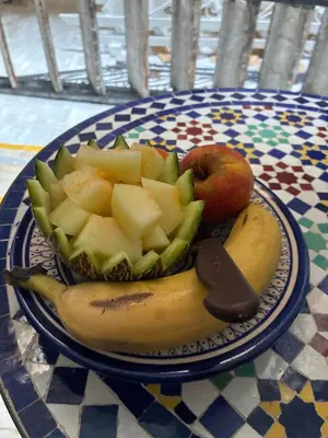 a plate of fruit on a table with a banana and apples at Riad Serendipity in Fès