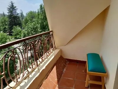 a green chair sitting on a balcony with a view at Centrical apartment in Ifrane forest and park view in Ifrane