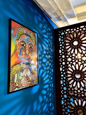 a painting on a blue wall next to two lights at cosy appartement calme in Oulad Akkou