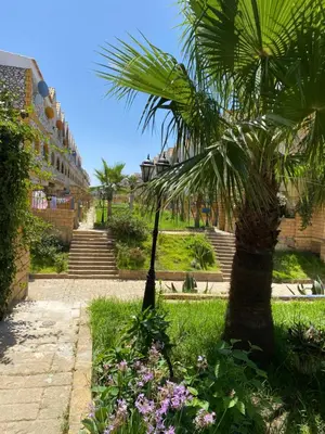 a palm tree and flowers in a park at Maison villa in Oulad Akkou