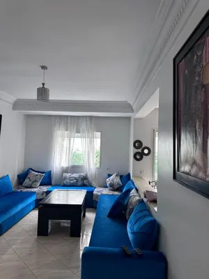 a living room with blue couches and a table at Appartment propre in Oulad Akkou