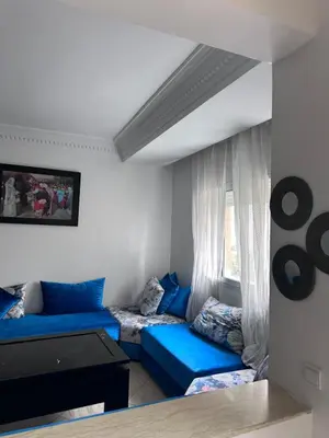 a living room with blue couches and a window at Appartment propre in Oulad Akkou