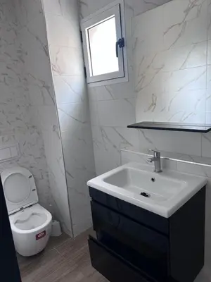 a bathroom with a sink and a toilet and a window at Appartment propre in Oulad Akkou