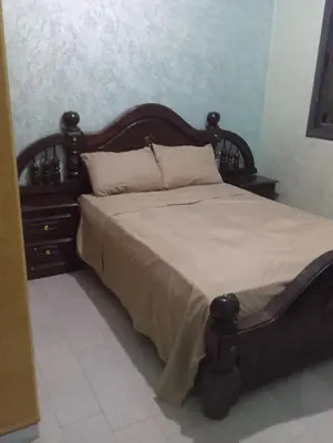 a bedroom with a large bed with a wooden headboard at Residence de repos in Oulad Tayeb