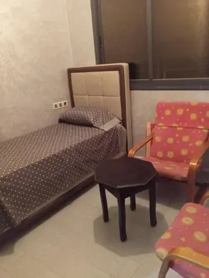 a room with a bed and a chair and a table at Residence de repos in Oulad Tayeb