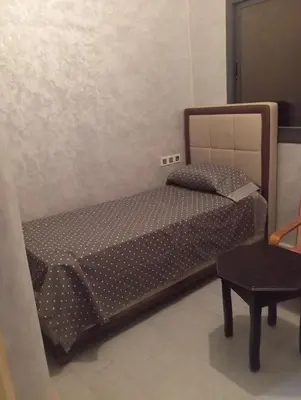 a small bedroom with a bed and a chair at Residence de repos in Oulad Tayeb