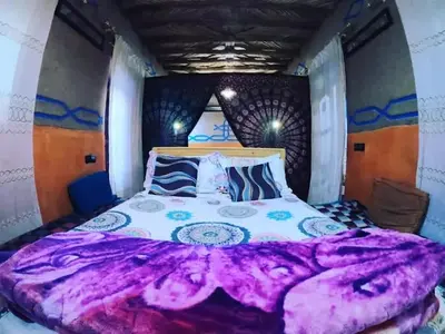 a bedroom with a large bed with a purple blanket at Home khamlia in Merzouga