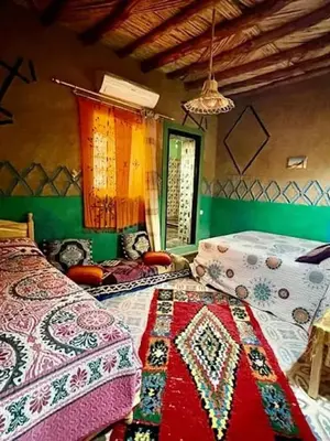 a bedroom with two beds with colorful blankets at Home khamlia in Merzouga
