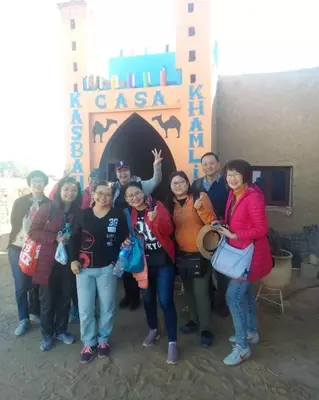 a group of people standing in front of a building at Home khamlia in Merzouga