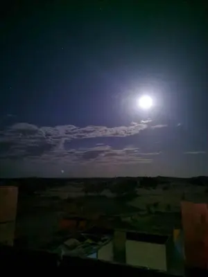a full moon in the sky over a field at Home khamlia in Merzouga