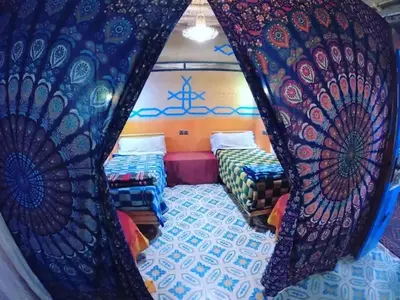 a bedroom with two beds and a curtain at Home khamlia in Merzouga