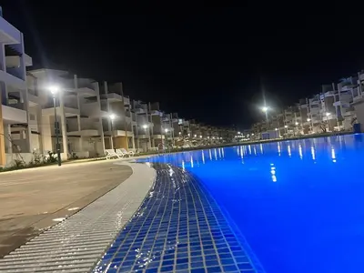a large swimming pool with blue water at night at Appartement in Oulad Akkou