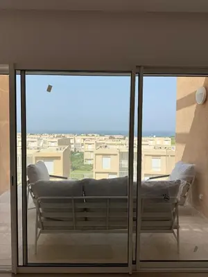 a large glass window with a couch on a balcony at luxurious Taghazout duplex in Oulad Akkou