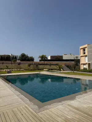 a large swimming pool with a wooden deck at luxurious Taghazout duplex in Oulad Akkou