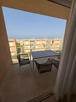 a balcony with a table and chairs and a large window at luxurious Taghazout duplex in Oulad Akkou