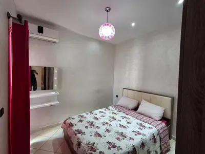 a bedroom with a bed with a floral bedspread at yas appart in Oulad Akkou