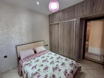 a bedroom with a bed with a floral bedspread at yas appart in Oulad Akkou