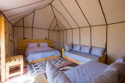 a room with two beds and a couch in a tent at lina safari luxury camp in Merzouga