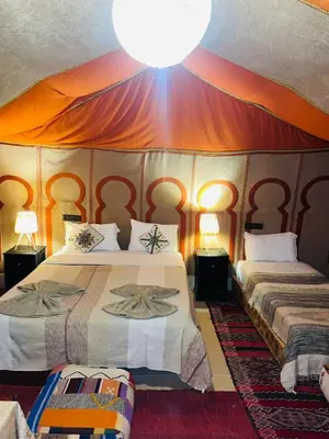 a bedroom with two beds in a tent at lina safari luxury camp in Merzouga