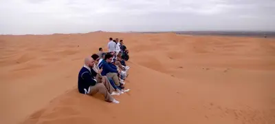 a group of people sitting in the desert at lina safari luxury camp in Merzouga
