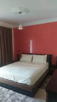 a bedroom with a large bed with a red wall at Complexe OCEAN ATLANITIQUE in Oulad Akkou