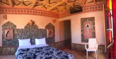 a bedroom with a bed and a chair in a room at Hotel KASBAH DADES MGOUN in Kalaat MGouna