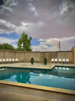 a swimming pool with chairs and a wall with at Hotel KASBAH DADES MGOUN in Kalaat MGouna