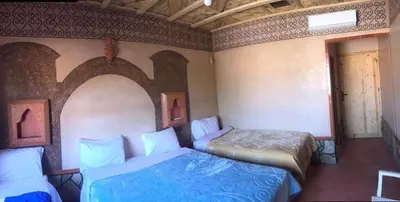 a room with two beds and a door with a window at Hotel KASBAH DADES MGOUN in Kalaat MGouna