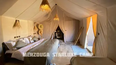 a bedroom with a tent with a bed and a couch at Merzouga Starluxe Camp in Merzouga