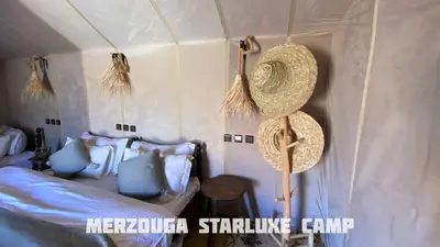 a bedroom with a bed and straw hats on the wall at Merzouga Starluxe Camp in Merzouga