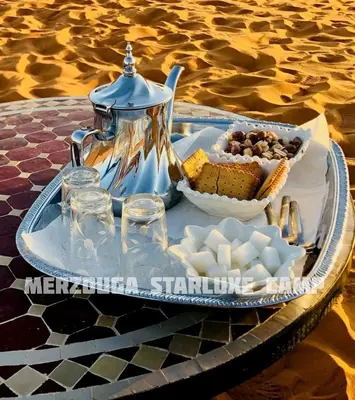 a tray with a tea kettle and a bowl of food at Merzouga Starluxe Camp in Merzouga