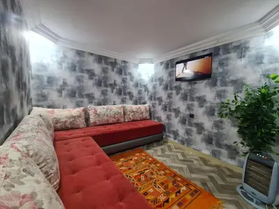 a living room with a red couch and a tv at House Silya in Oulad Akkou