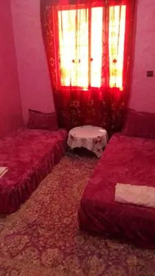 a bedroom with two beds and a window with red curtains at Appartement à Agadir in Azrou
