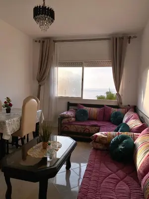 a living room with a couch and a table at Facing the sea, close to the Corniche in Oulad Akkou