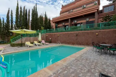 a pool in front of a building with a table and chairs at Marrakech Le Joyau de l'ourika in Ourika