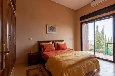 a bedroom with a bed and a large window at Marrakech Le Joyau de l'ourika in Ourika