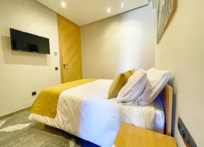 a bedroom with a bed with white sheets and pillows at Luxury Modern Studio with Netflix, Kitchen and Free Parking Elite Garden, Marrakesh in Aït Saïd