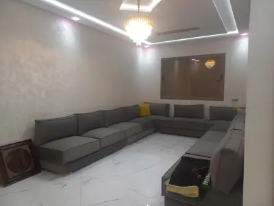 a living room with a couch and a projection screen at JOLIE APPART à BOUZNIKA in Oulad Akkou