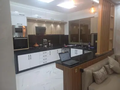 a kitchen with white cabinets and a laptop on a counter at JOLIE APPART à BOUZNIKA in Oulad Akkou