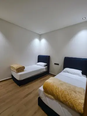 two beds in a room with white walls and wooden floors at appartement luxueux khenifra 1 in Khenifra