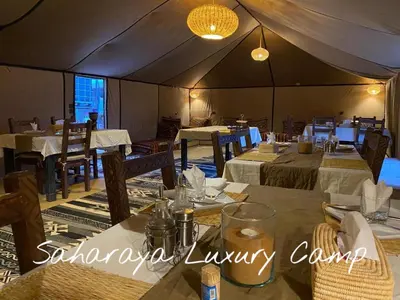 a dining room with tables and chairs in a tent at Sahary Tafilalt Luxury Camp in Merzouga